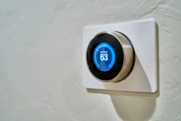 A modern smart thermostat on a wall representing energy efficient heating controls for domestic EPC assessments